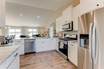 Kitchen shown with white cabinets, gas oven/range, microwave over cooktop, and quartz countertops. Photos is of model home. Colors and options may vary. Ask Sales Agent for details. | Image 3