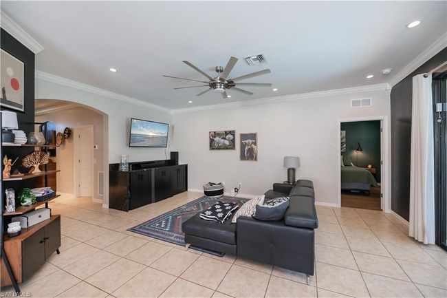 Living area featuring light tile patterned floors, arched walkways, ceiling fan, and visible vents | Image 7