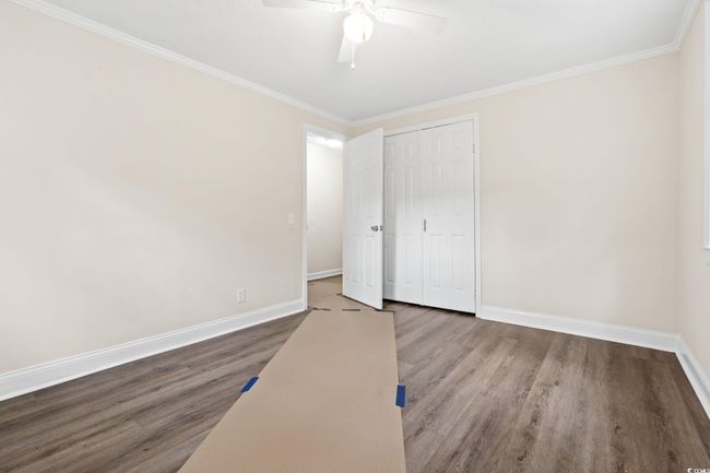Unfurnished bedroom featuring wood finished floors, baseboards, ornamental molding, a closet, and ceiling fan | Image 31