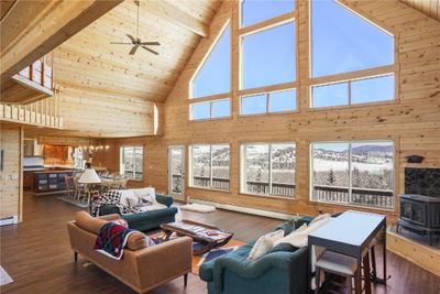 Living room with a healthy amount of sunlight, ceiling fan, a wood stove, and high vaulted ceiling | Image 2