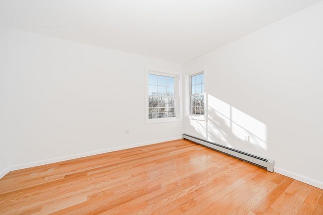 Spare room with baseboards, wood finished floors, and baseboard heating | Image 17