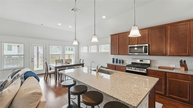 Kitchen with appliances with stainless steel finishes, dark wood finished floors, open floor plan, a breakfast bar, and backsplash | Image 18