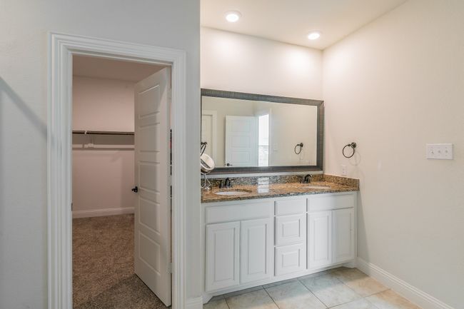 Bathroom with double vanity, a spacious closet, baseboards, and a sink | Image 31