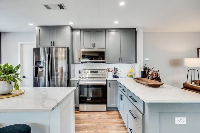 Kitchen featuring appliances with stainless steel finishes, gray cabinets, a peninsula, and recessed lighting | Image 10