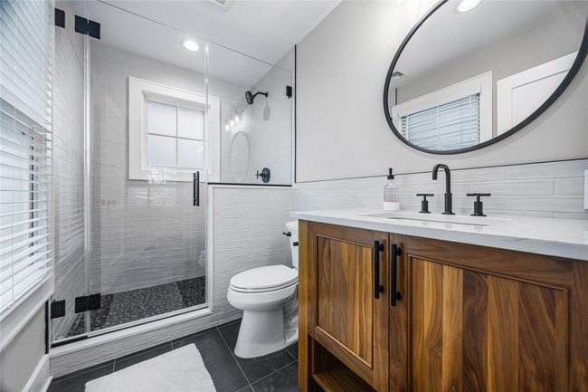 Bathroom featuring toilet, vanity, a stall shower, and tile walls | Image 32