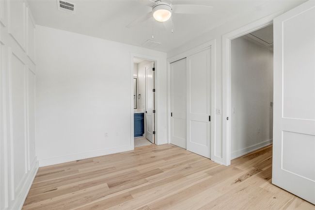 Unfurnished bedroom featuring light wood finished floors, baseboards, ensuite bathroom, and a ceiling fan | Image 25