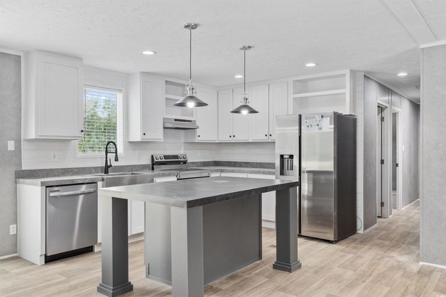 Kitchen featuring appliances with stainless steel finishes, under cabinet range hood, open shelves, white cabinetry, and light wood finished floors | Image 13