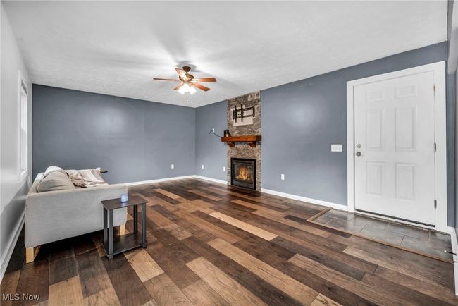 Living room featuring ceiling fan, wood finished floors, and a stone surround on a gas fireplace | Image 16