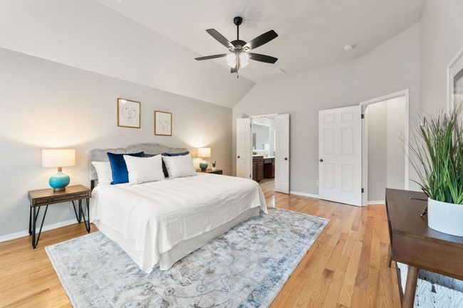Bedroom featuring lofted ceiling, light wood-style floors, ceiling fan, and ensuite bath | Image 25