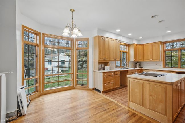 Kitchen with a sink, pendant lighting, light wood finished floors, light countertops, and a notable chandelier | Image 11
