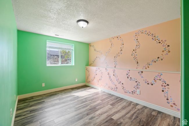Empty room featuring a textured ceiling, visible vents, wood finished floors, and baseboards | Image 23