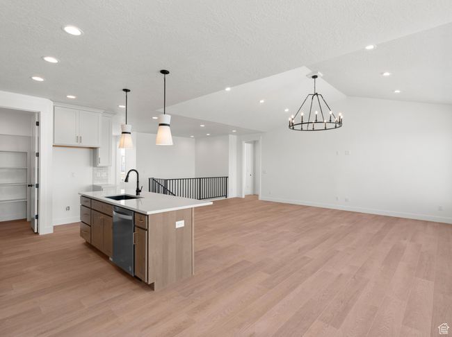 Kitchen featuring open floor plan, light countertops, light wood-type flooring, stainless steel dishwasher, and a sink | Image 8