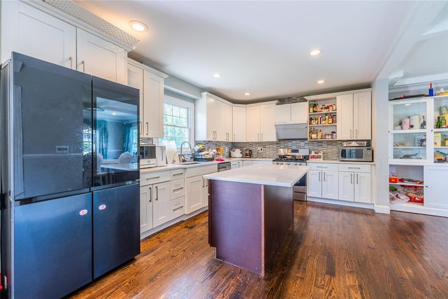 Kitchen featuring stainless steel appliances, light countertops, dark wood-style flooring, decorative backsplash, and recessed lighting | Image 18