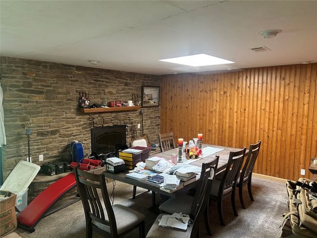Dining area featuring carpet floors, wooden walls, sky light, and a stone fireplace | Image 16