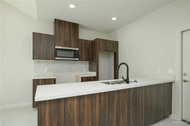Kitchen with stainless steel microwave, light marble finish floors, a sink, modern cabinets, and a peninsula | Image 7