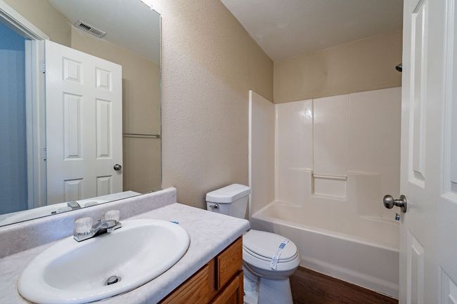 Full bath with toilet, wood finished floors, vanity, a textured wall, and shower / tub combination | Image 27