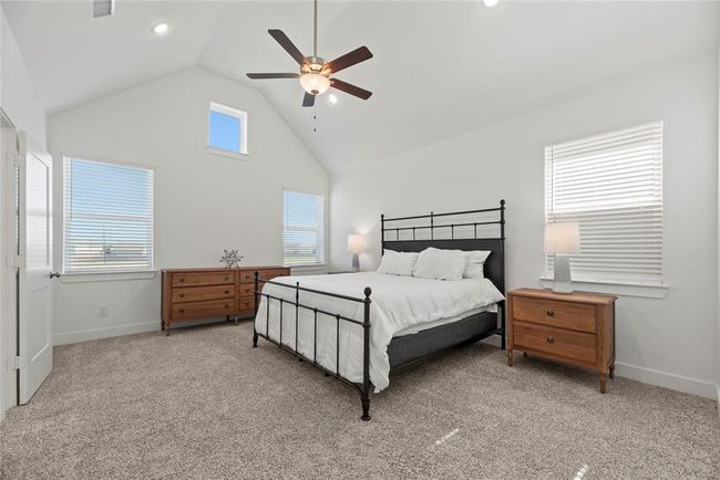The large primary bedroom is conveniently located upstairs and features a high ceiling, ceiling fan, plush carpet and an en-suite bathroom. | Image 13