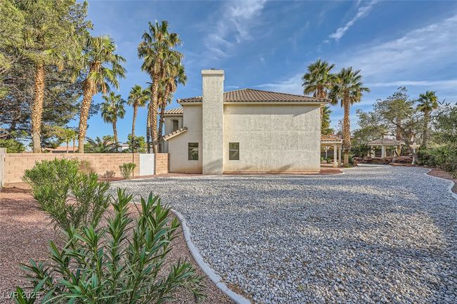 Rear view of property with a chimney, stucco siding, a gazebo, fence, and a tiled roof | Image 51