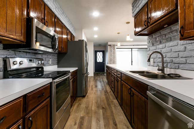 Kitchen with stainless steel appliances, a sink, light countertops, dark wood-style flooring, and recessed lighting | Image 13
