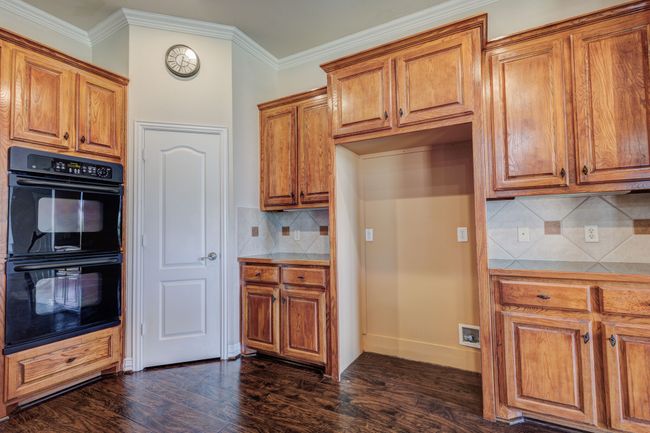 Kitchen featuring dark hardwood / wood-style flooring, double oven, ornamental molding, and tasteful backsplash | Image 26