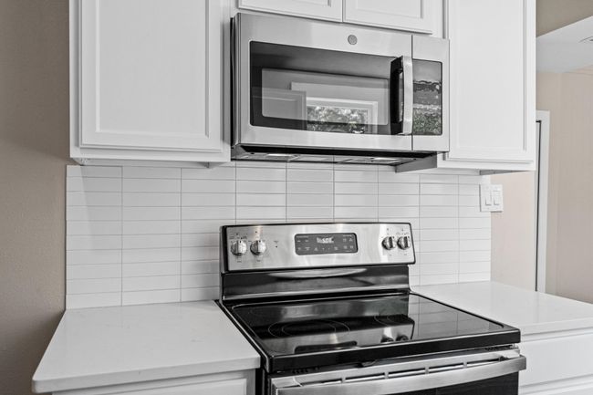 Kitchen with appliances with stainless steel finishes, tasteful backsplash, light countertops, and white cabinetry | Image 7