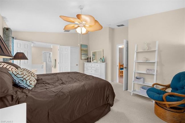 Bedroom with light colored carpet, visible vents, vaulted ceiling, a ceiling fan, and ensuite bath | Image 23
