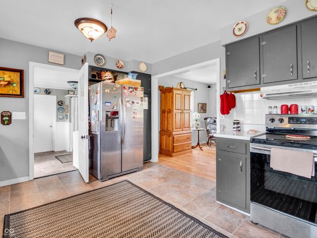 kitchen with under cabinet range hood, tasteful backsplash, baseboards, gray cabinetry, and appliances with stainless steel finishes | Image 13