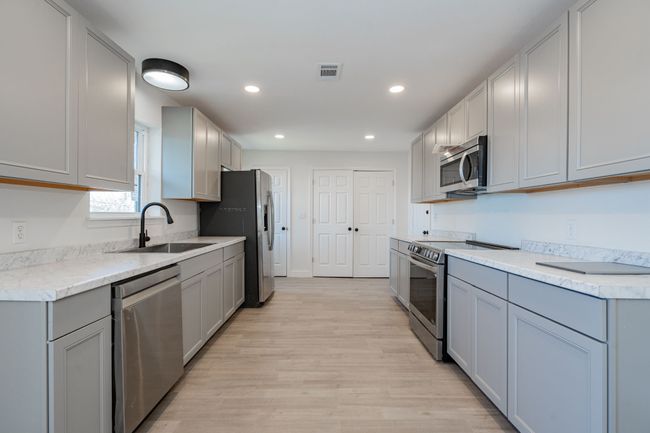 Kitchen with stainless steel appliances, gray cabinets, light wood-style floors, recessed lighting, and light countertops | Image 8