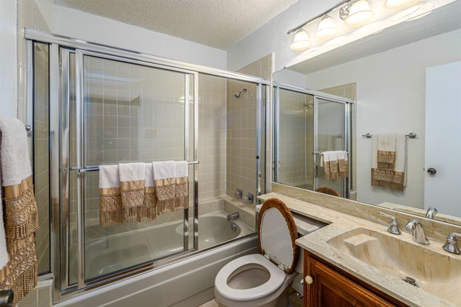 Full bathroom with toilet, vanity, a textured ceiling, and combined bath / shower with glass door | Image 13