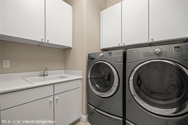 Washroom featuring cabinet space, washer and dryer, and a sink | Image 48