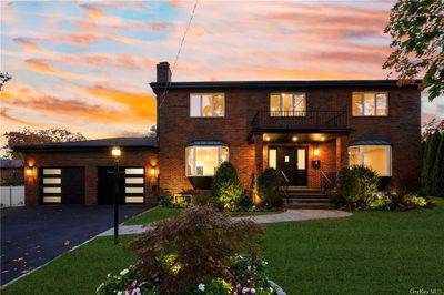 View of front facade featuring a balcony, a garage, and a lawn | Image 1