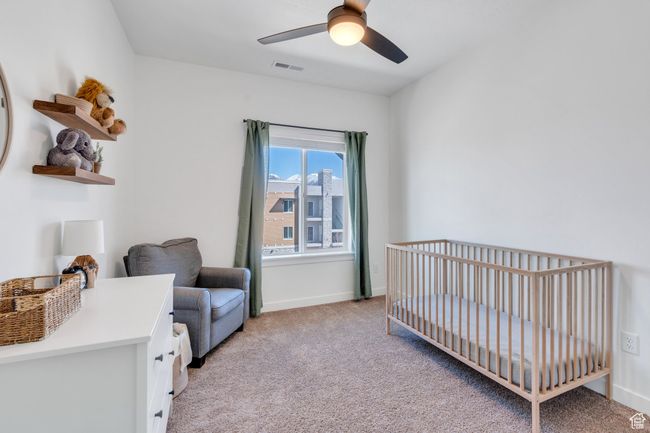 Bedroom featuring visible vents, baseboards, a nursery area, ceiling fan, and light colored carpet | Image 13