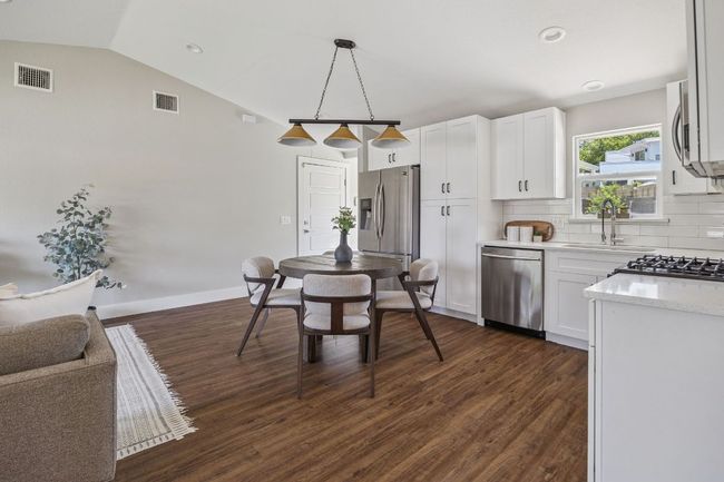 Kitchen with stainless steel appliances, dark wood-style flooring, backsplash, white cabinetry, and pendant lighting | Image 10