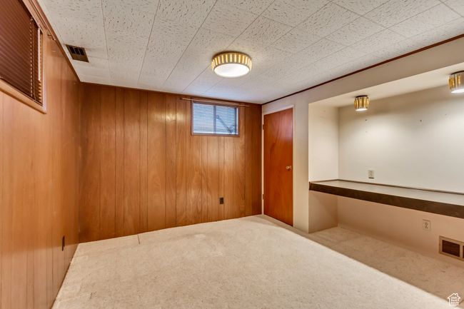 Basement with wooden walls, visible vents, and carpet flooring | Image 20