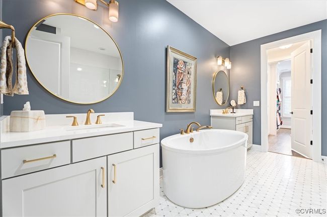Full bath featuring baseboards, two vanities, a freestanding tub, and a sink | Image 24
