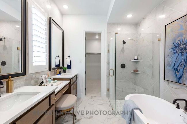 Full bath featuring marble look tiles, a marble finish shower, a freestanding bath, vanity, and a walk in closet | Image 15