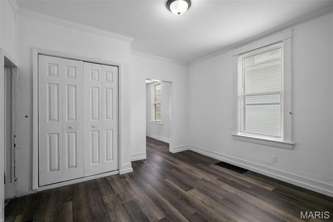 Unfurnished bedroom featuring ornamental molding, a closet, and dark wood finished floors | Image 6