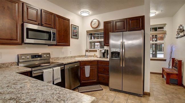 Kitchen with breakfast bar, range, refrigerator, dishwasher, microwave and plenty of storage | Image 16