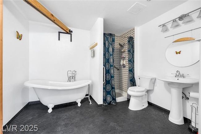 Bathroom featuring toilet, a shower stall, a freestanding tub, baseboards, and a sink | Image 12