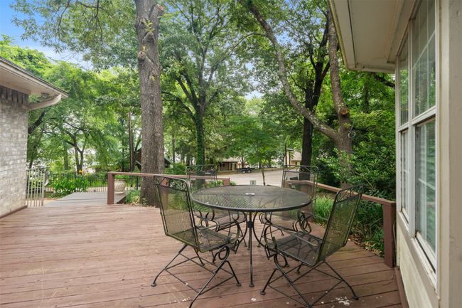 Wooden deck featuring outdoor dining space and view of wooded area | Image 5