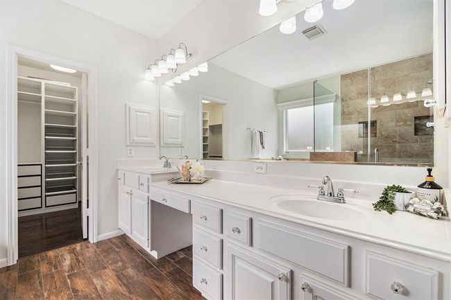 A spa-like primary ensuite awaits you! A unique dual sink vanity with varying height and knee space with cabinets and drawers for storage, is ideal for those mornings of sitting down and preparing for the day! And sneak a peek at the primary closet with custom built-ins! | Image 13