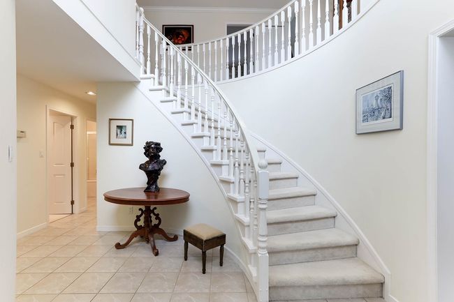 Staircase with tile patterned flooring, a towering ceiling, and baseboards | Image 23