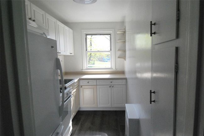 Kitchen featuring dark wood-type flooring, light countertops, gas range gas stove, and white cabinetry | Image 7