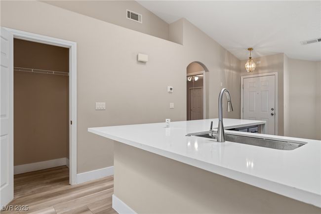 Kitchen featuring arched walkways, hanging light fixtures, light stone counters, and light wood finished floors | Image 18