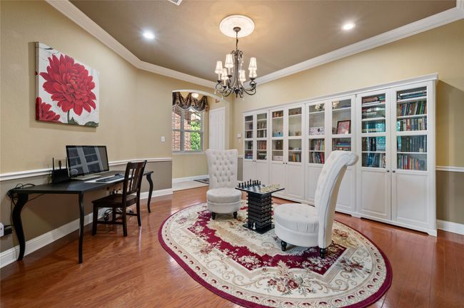 Dining space with a chandelier, wood finished floors, crown molding, an office area, and recessed lighting | Image 6