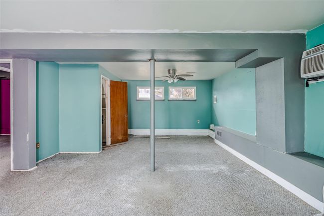 Basement featuring a ceiling fan, an AC wall unit, visible vents, and baseboards | Image 28