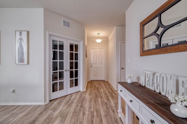Hallway with baseboards, visible vents, french doors, and light wood finished floors | Image 6