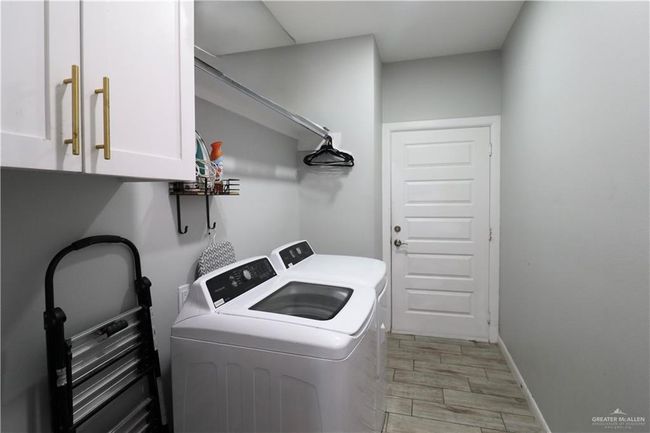 Laundry room featuring cabinet space, washing machine and clothes dryer, light wood-style flooring, and baseboards | Image 18