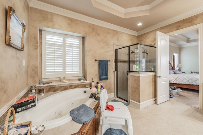 Ensuite bathroom with a whirlpool tub, a shower stall, ornamental molding, and tile patterned flooring | Image 23