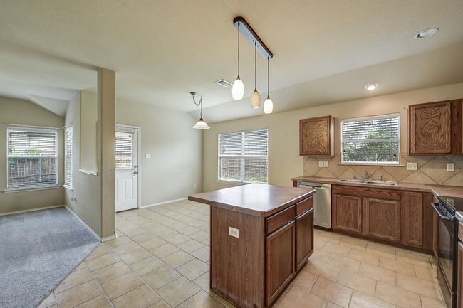 Kitchen with decorative backsplash, pendant lighting, a kitchen island, and brown cabinetry | Image 14